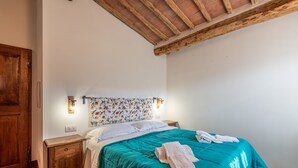 Ein Schlafzimmer mit himmelblauer Bettdecke, Nachttisch aus Holz und einem blumengemusterten Kopfteil.