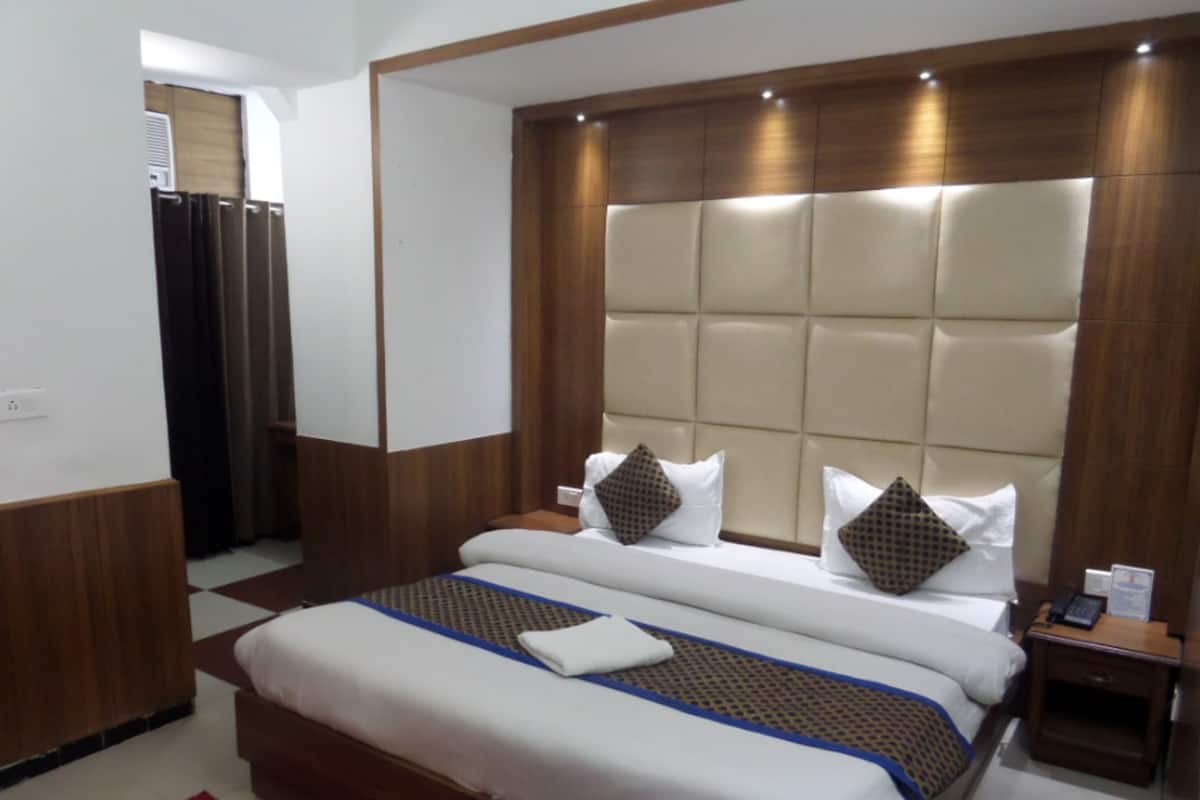 Une chambre d’hôtel avec un grand lit, une tête de lit en bois et un tapis rouge.