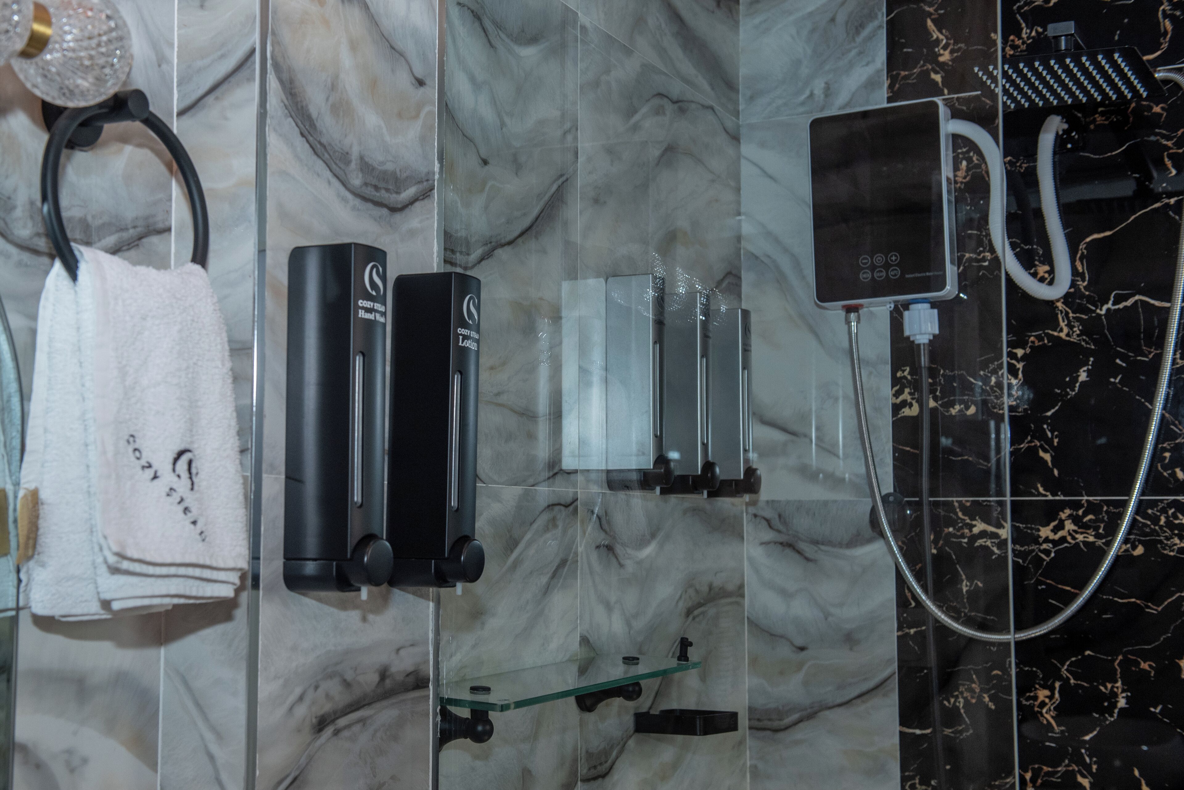 A bathroom with a marble backsplash, a towel rack with a towel, a handheld showerhead, and a handheld massager.