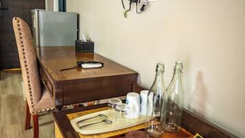 Een houten eettafel met een afstandsbediening, zout- en peperstel, twee glazen flessen en een dienblad met bestek.