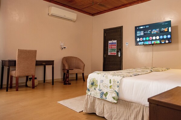 A hotel room with a bed, a desk, a chair, a television, and a fire action poster on the wall. -  Cozy Stead Hotel - Haven House, Gigiri (Nairobi)