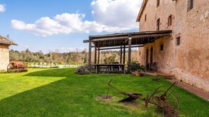 Ein rustikales Gebäude mit einer überdachten Veranda, einem grünen Rasen und einem historisch anmutenden Wagen.