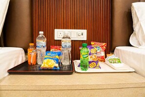 A hotel room with a tray table set with snacks, drinks, and a bottle of water. - Laxmi Vilas (Varanasi)