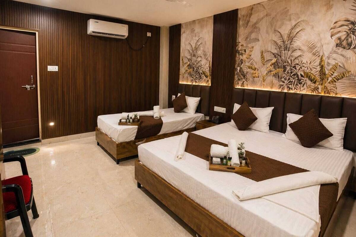 Een hotelkamer met twee bedden, een plafondventilator, een airconditioning en een muurschildering.