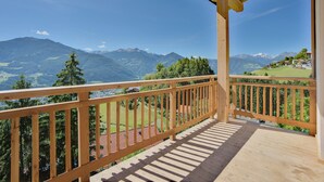 Un balcón de madera con vistas a un paisaje montañoso.
