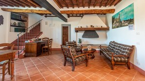 Una sala de estar con chimenea, muebles de madera, una escalera y un comedor.