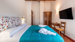 Un dormitorio con cama, escritorio, silla, televisor y armario.
