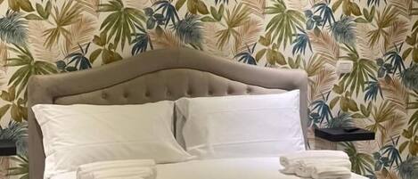 A bed with a tufted headboard, white bedding, and neatly folded towels.