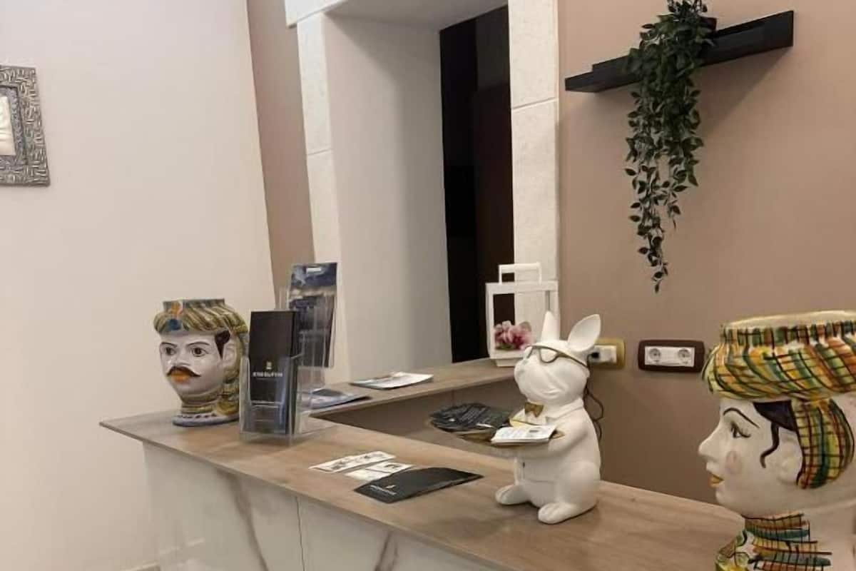 A reception desk with a marble counter, a white ceramic rabbit figurine, and a decorative head sculpture.