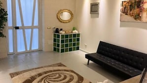 A hotel lobby with a reception desk, a black sofa, a green decorative cabinet, and a large window with curtains. - Melody rooms (Syracuse)