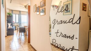 A hallway with a whiteboard displaying 'les grands trans-Parent' and framed pictures on the wall. - Desire for the Sea (Gallipoli)