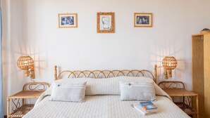 A bedroom with a bed, two bedside tables, and three framed pictures on the wall. - Desire for the Sea (Gallipoli)