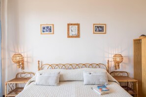Ein Schlafzimmer mit einem Bett, zwei Nachttischen und drei gerahmten Bildern an der Wand.