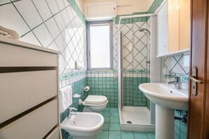 Ein Badezimmer mit einer Bidet-Einrichtung, Toilette und Waschbecken.