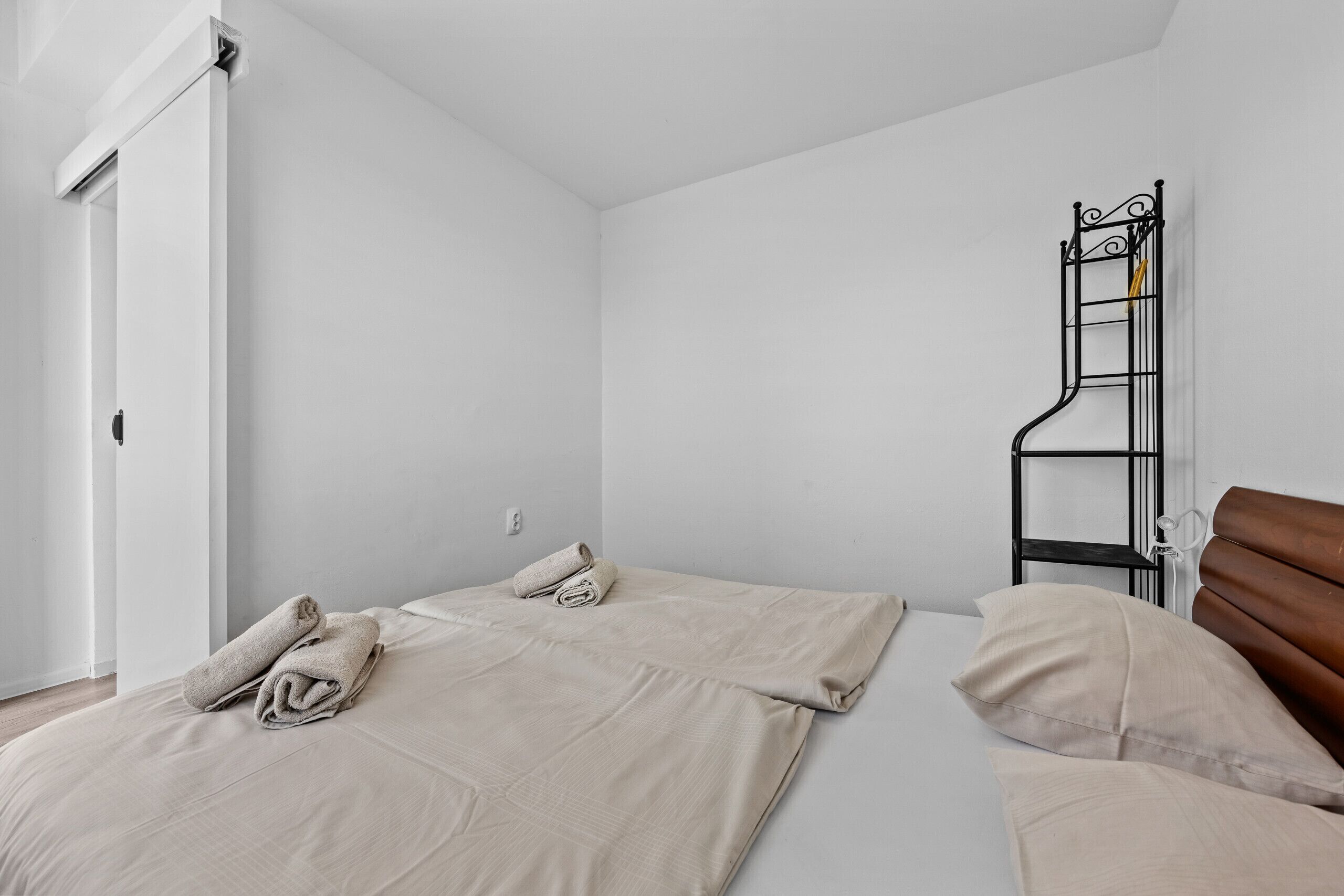 A simple, clean room with two beds, a wooden headboard, and a metal ladder against the wall.