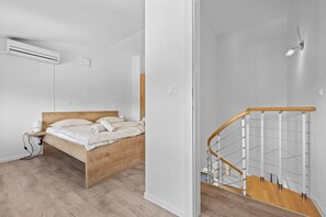 A bedroom with a wooden bed, a nightstand, an air conditioner, and a staircase with a wooden railing. - Apartment Susanne 2 with Shared Pool near Porec (Kukci)