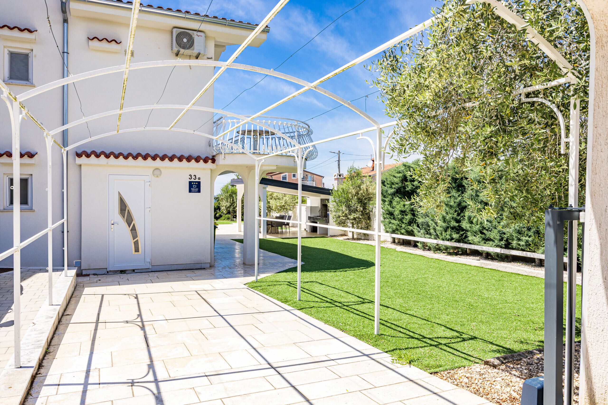 A building with a covered entrance, a small balcony, and a well-maintained lawn.