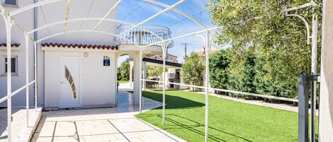 A building with a covered entrance, a small balcony, and a well-maintained lawn.