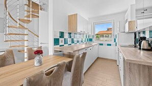 A modern kitchen with a central island, white cabinetry, and a spiral staircase. - Apartment Susanne 2 with Shared Pool near Porec (Kukci)