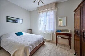 A bedroom with a bed, a chair, a bedside table with a mirror, and a wardrobe. - Villa Les Mouettes - 50 m from the beach (Bernières-sur-Mer)