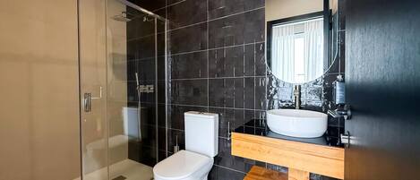 Une salle de bain moderne avec une douche à parois de verre, des toilettes blanches et un meuble-lavabo en bois avec un évier.