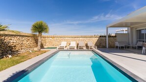 A rectangular swimming pool with clear blue water, surrounded by a stone wall and a white pergola. - Villa Ginevra: Exclusive Luxury and Wellbeing Near Otranto (Otranto)
