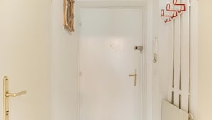 Une porte blanche avec une poignée dorée, un radiateur blanc et un téléphone fixé au mur.
