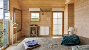 Una habitación de madera con cama, radiador, ventana y puerta.