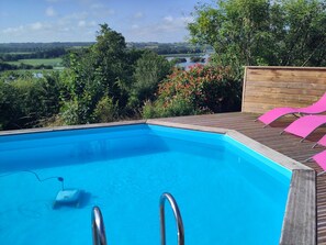 Une piscine avec une terrasse en bois et des chaises longues roses.