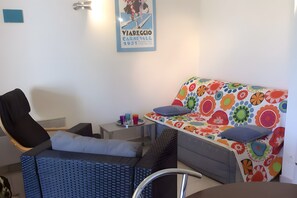 A room with a bed, a chair, a small table, and a wall-mounted light fixture. - Modern 2-Bedroom Apartment with Terrace near Calvi Beach and Center (Calvi)