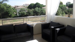 A balcony with two black wicker sofas and a white curtain. - Modern T3 Apartment in Calvi with Terrace – Available from August 22, Discounted Rates (Calvi)