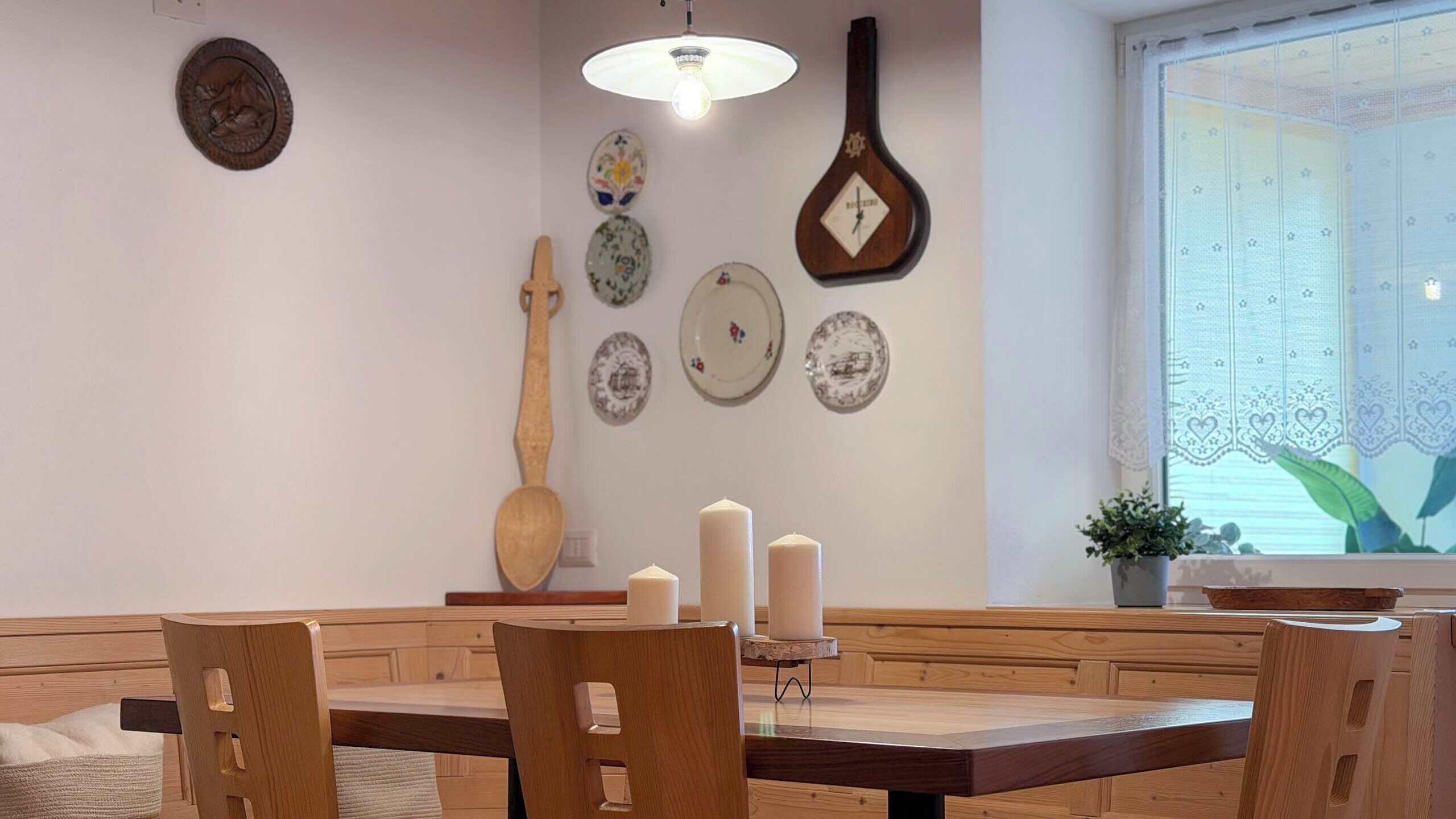 A dining area with wooden furniture, a wall-mounted clock, and decorative plates.