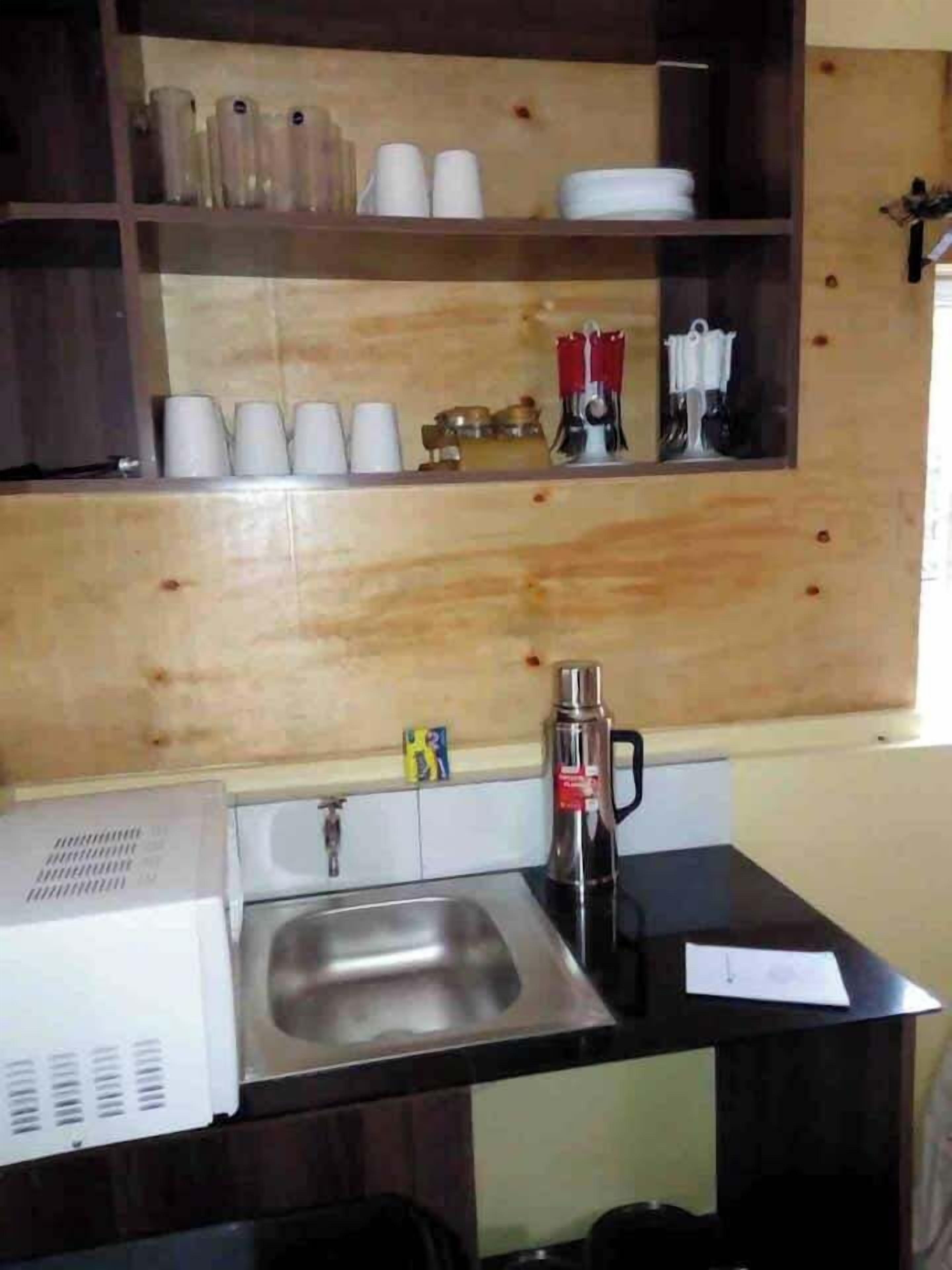 A compact kitchen with wooden cabinets, a stainless steel sink, and a microwave.