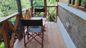 Un terrazzo in legno con tavolo e sedie, affacciato su una zona boschiva.