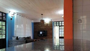Un'ampia hall con una reception in marmo, una TV a schermo piatto montata a parete e un'ampia finestra con tende.