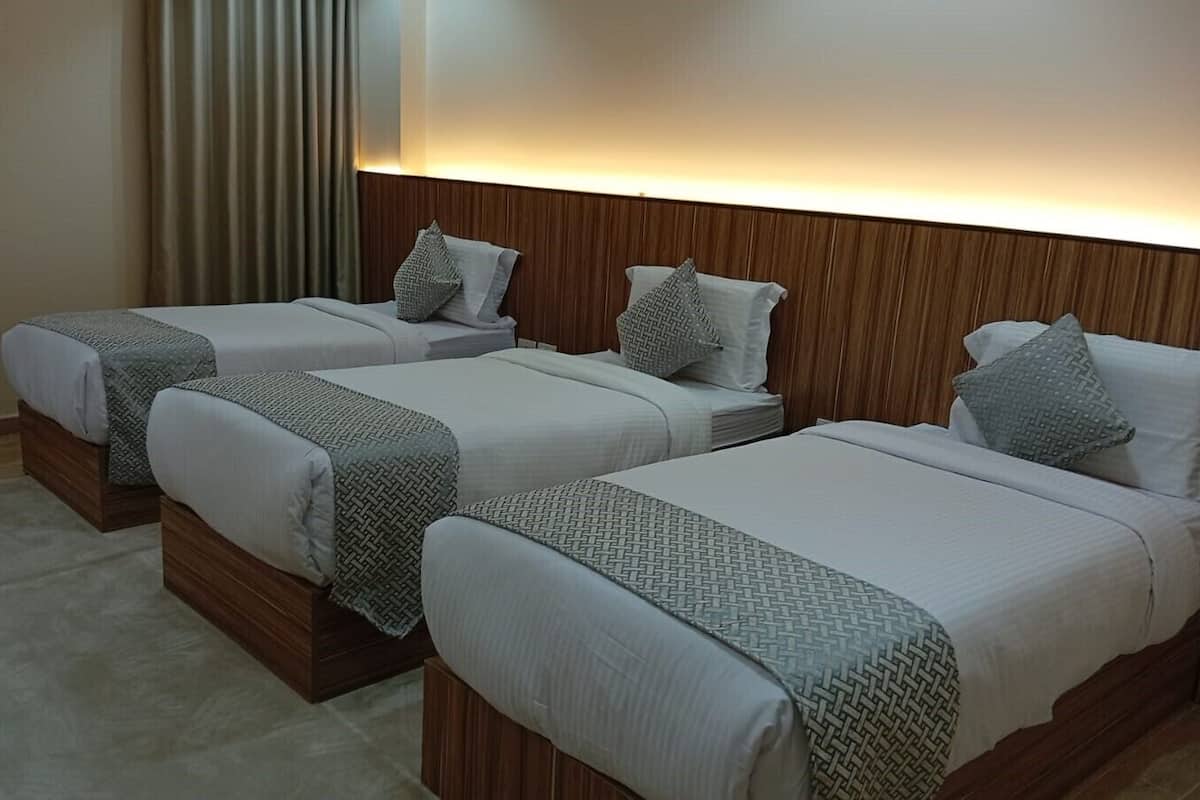 Ein Hotelzimmer mit drei Betten, Holzkopfteilen und einem hellen Teppich.