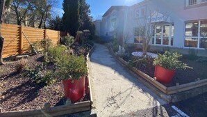 A pathway leading to a building with a sign that reads "restaurant." There are potted plants along the path and a wooden fence on the left. - hôtel olympe (Aix-en-Provence)