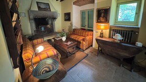 A cozy living room with a fireplace, a sofa set, a wooden table, and a vintage bathtub. - Country house with pool in Anghiari Arezzo (Anghiari)