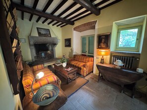 A cozy living room with a fireplace, a sofa set, a wooden table, and a vintage bathtub. - Country house with pool in Anghiari Arezzo (Anghiari)