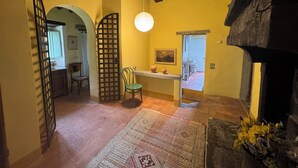 A room with a wooden ceiling, a green chair, a table with vases, and a rug. - Country house with pool in Anghiari Arezzo (Anghiari)
