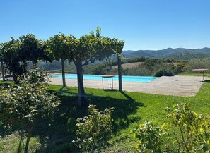 A pool area with a pergola, surrounded by greenery and hills in the background. - Country house with pool in Anghiari Arezzo (Anghiari)