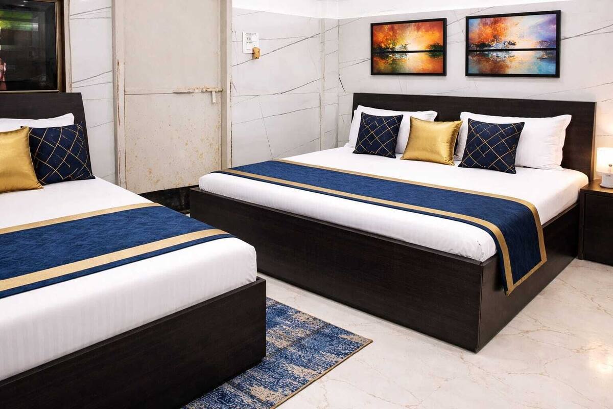 A hotel room with two beds, a marble floor, and artwork on the walls.