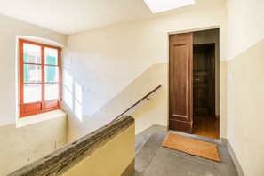 A staircase with a wooden handrail, a window with red shutters, and a door leading to another room. - San Pierino in Firenze (Florence)