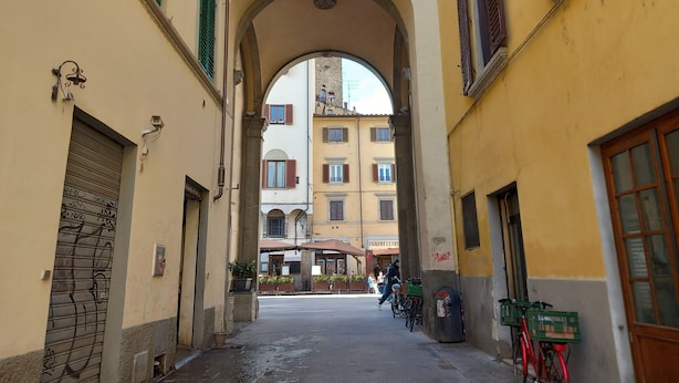Eine Stadtstraße mit einem stützenden Durchgang zu einem Gebäude mit mehreren Fenstern und Balkonen.