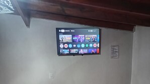 A room with a wooden floor, a TV mounted on the wall displaying various streaming services, and a small sign with text. - House for rent in mar del plata, per day, per week or per fortnight (Mar del Plata)
