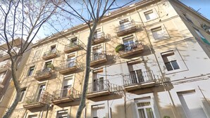 Ein mehrstöckiges Gebäude mit Balkonen, Fenstern und einem Baum im Vordergrund.