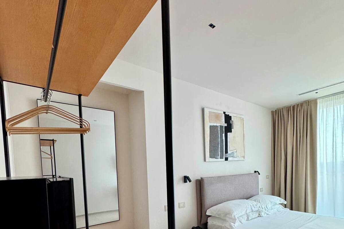 Une chambre d’hôtel moderne équipée d’un lit, d’une table de chevet et d’un bureau en bois avec une chaise noire.