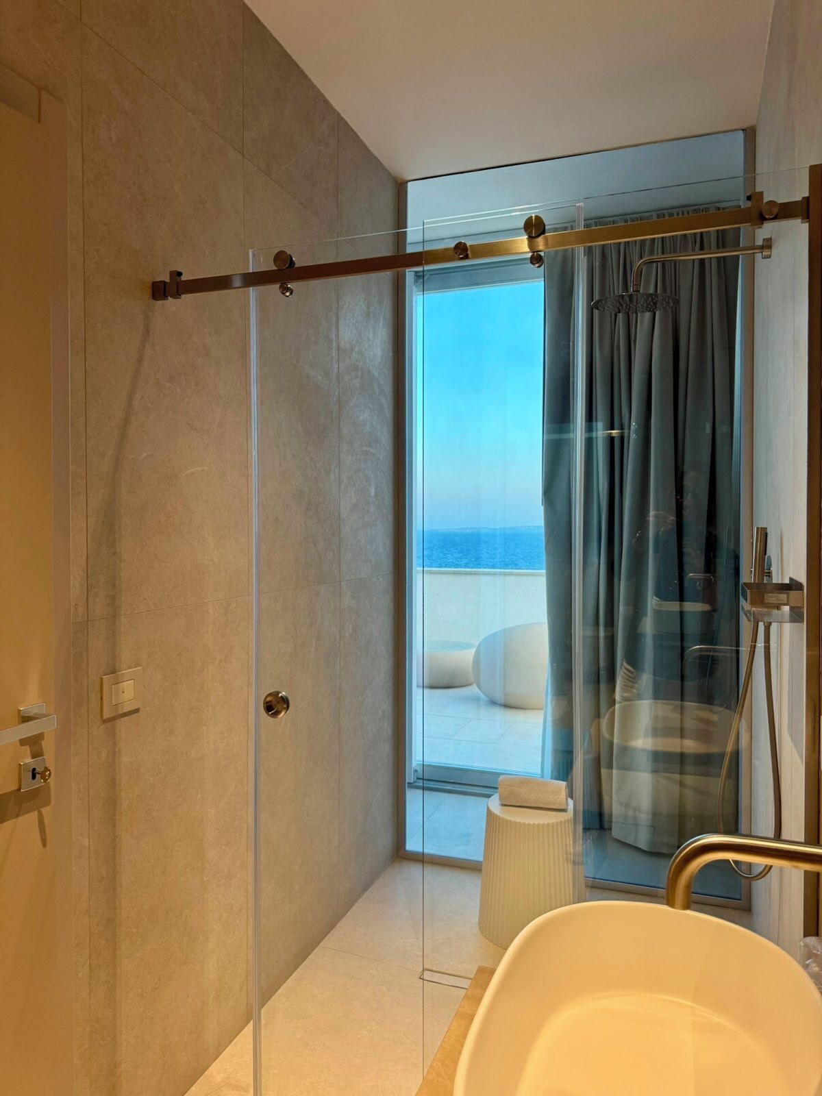 Ein modernes Badezimmer mit Duschkabine aus Glas, einer Badewanne und Meerblick.