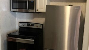 A kitchen with a stainless steel refrigerator, a microwave, and an oven.