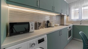 Eine kleine Küche mit Mikrowelle, Toaster, Wasserkocher und Waschmaschine.